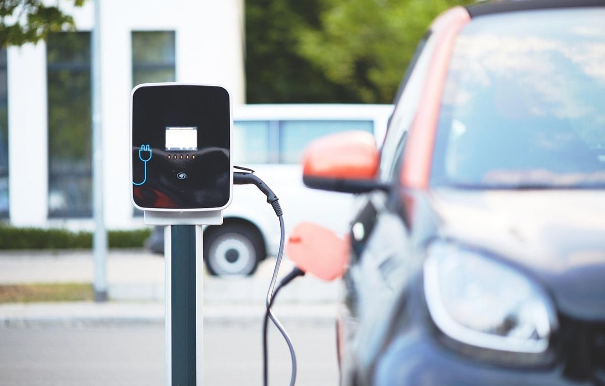 Station de recharge pour voiture électrique, câblée à un véhicule noir, rue urbaine