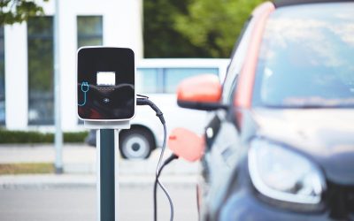 Station de recharge pour voiture électrique, câblée à un véhicule noir, rue urbaine