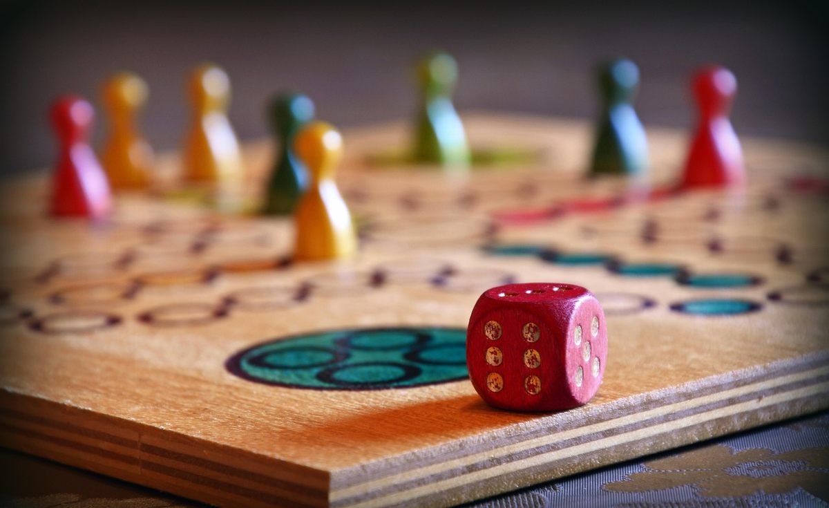 Un plateau de jeu en bois avec pièces colorées et un dé rouge