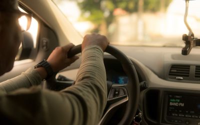 Un conducteur tient le volant, le tableau de bord et la radio sont visibles