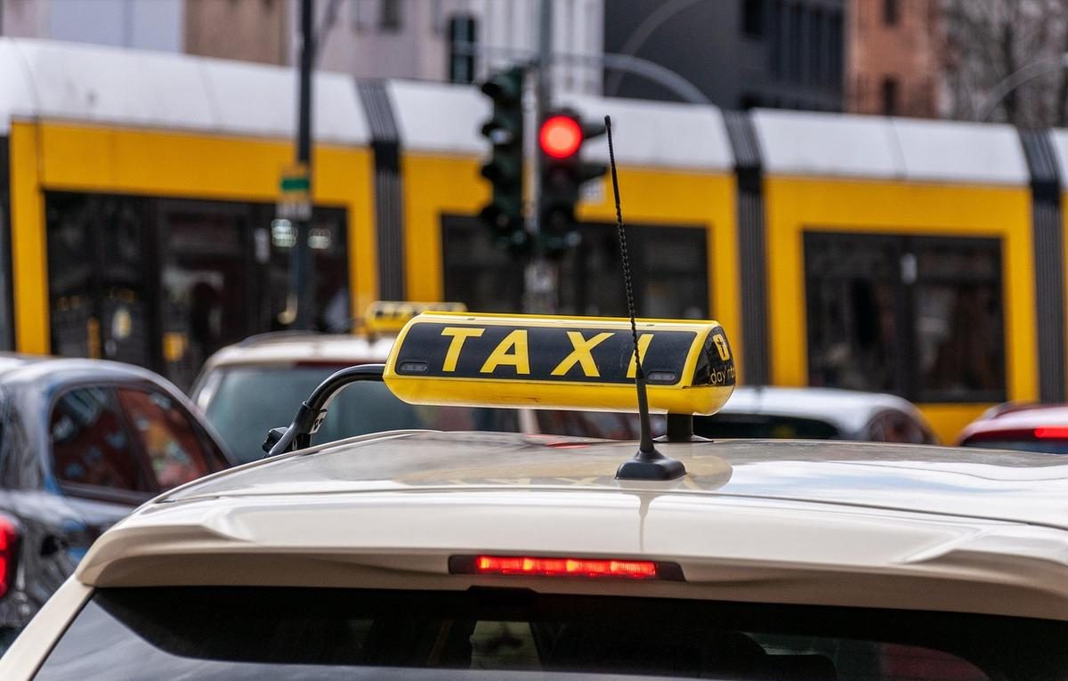 Un taxi avec son panneau jaune attend au feu rouge