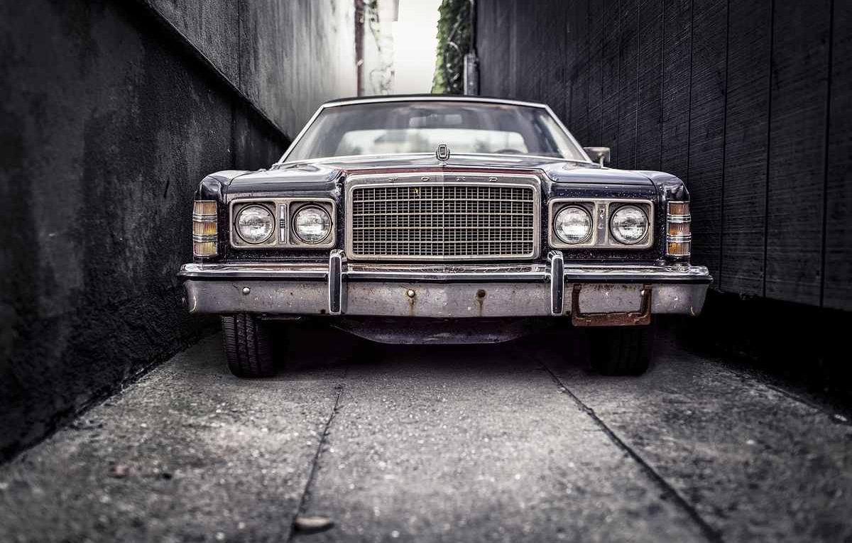 Une voiture vintage encadrée par des murs sombres dans une allée